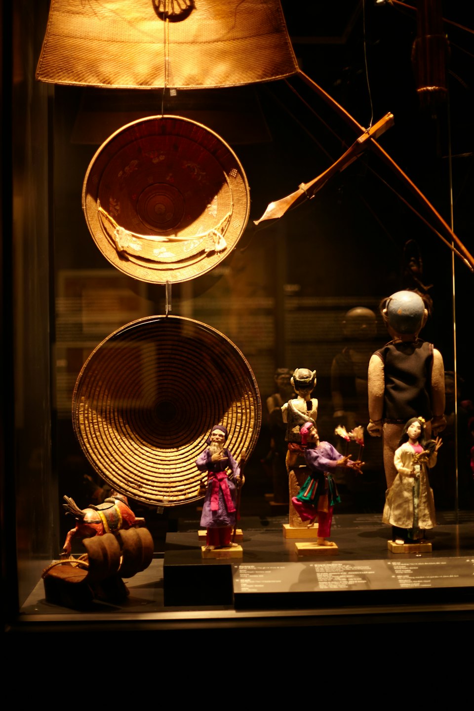 Artefactos culturales expuestos en una vitrina de museo con figurillas y cestas.
